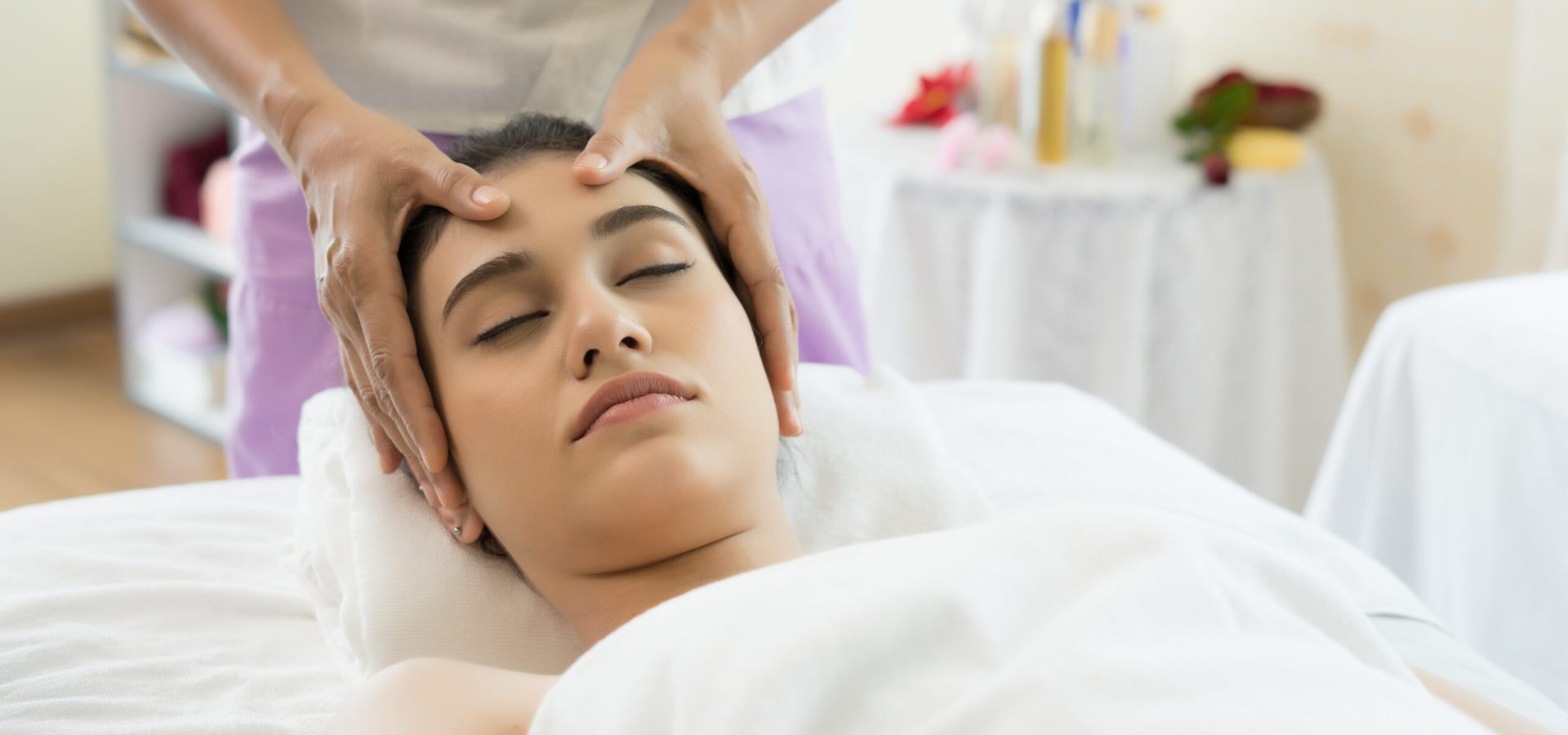 Young beautiful woman having face massage relaxing in spa.